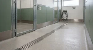 A concrete wash-down floor and drainage system inside a multi-dog kennel block to maintain UK hygiene standards.